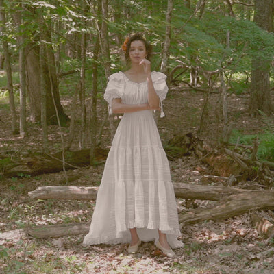 Movement video of Low. Sustainable wedding dress in  organic cotton with embroidery, elbow length puff sleeves, and tiered skirt with train.