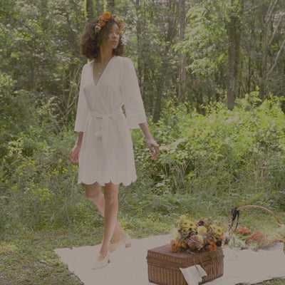 Movement video of Nola. Sustainable organic cotton robe with all over embroidery, scalloped hem and embroidered tie belt.